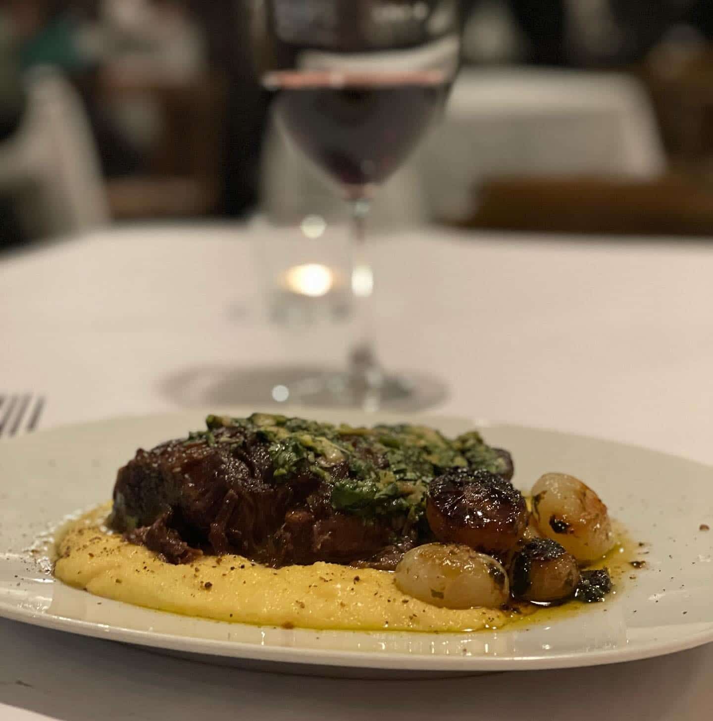 A Plate of Food With a Glass of Wine in the Background — Onesta Cucina in Bowral, NSW