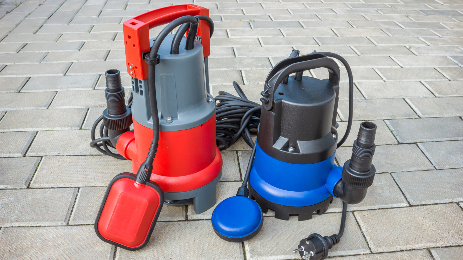 Two submersible pumps are sitting on a brick sidewalk.