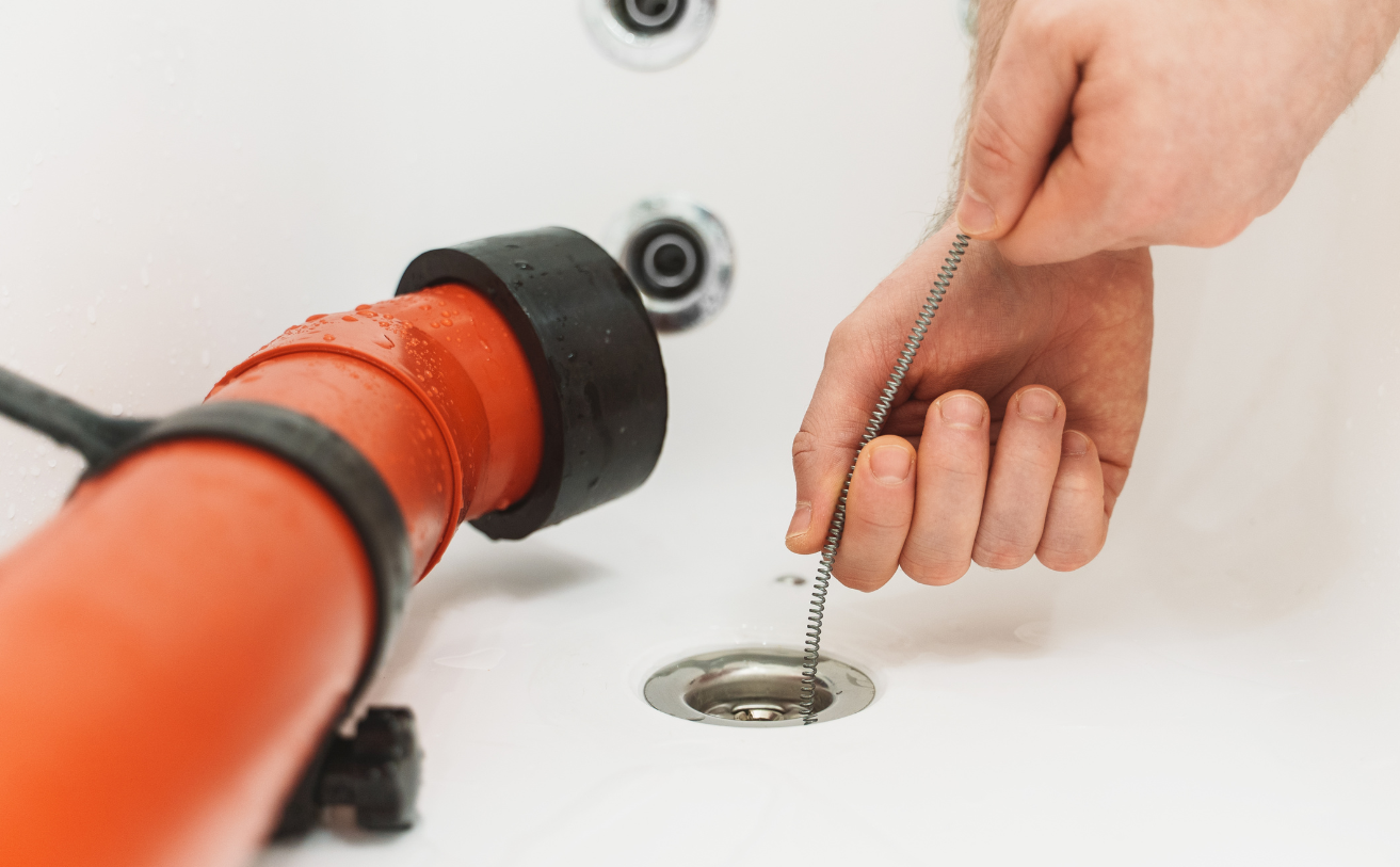 A person is cleaning a drain in a bathtub with a plunger.