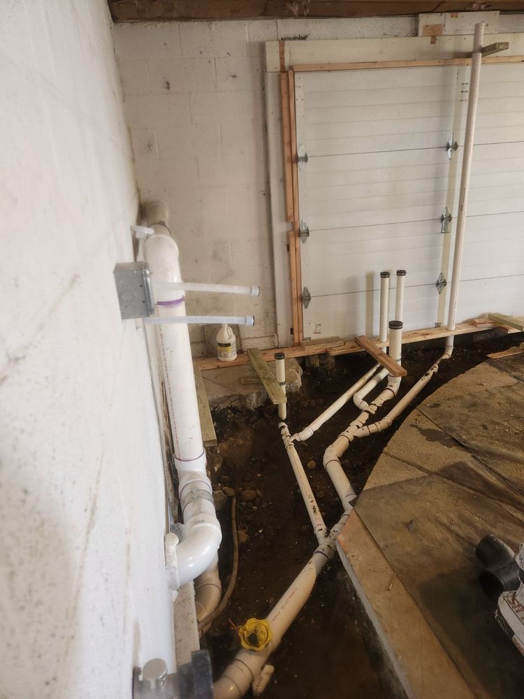 A bunch of pipes are connected to a wall in a basement.