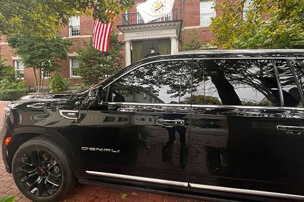 A black GMC Denali SUV parked in front of Jones Hall, which displays American and state flags.
