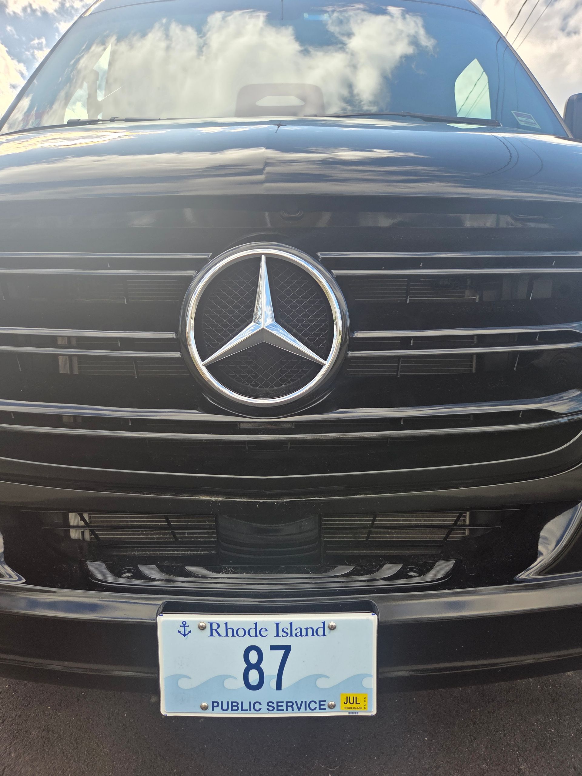Close-up of a black Mercedes-Benz front grille with a Rhode Island public service license plate reading 