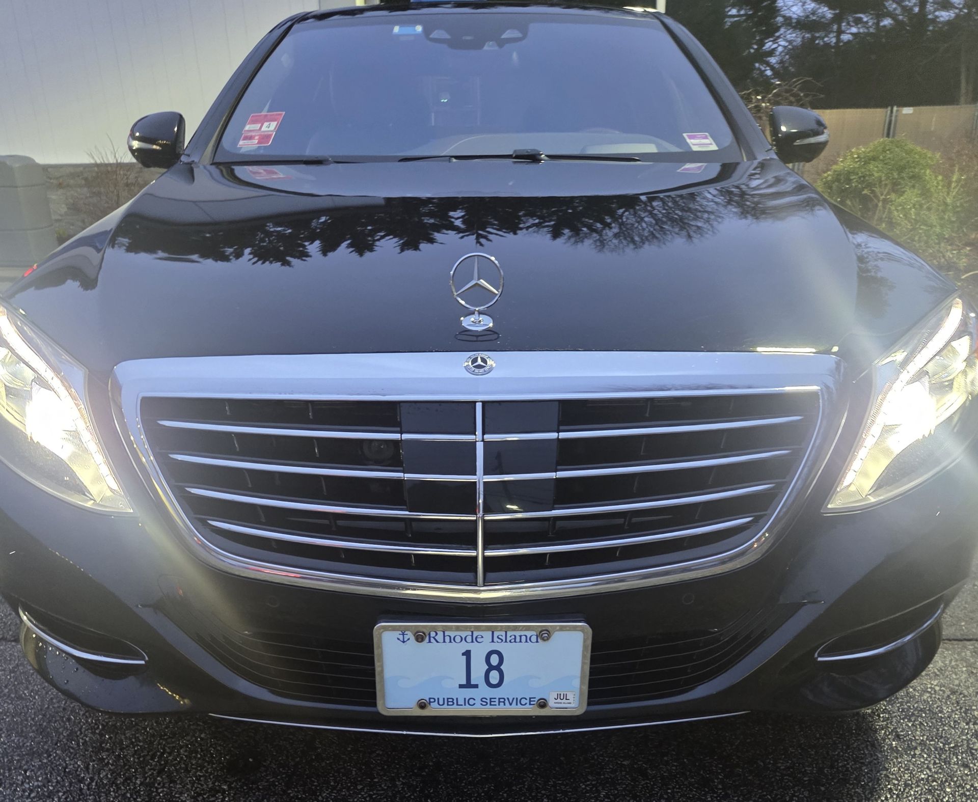 A front-facing view of a black Mercedes-Benz sedan featuring a chrome grille, hood ornament, and a license plate reading 