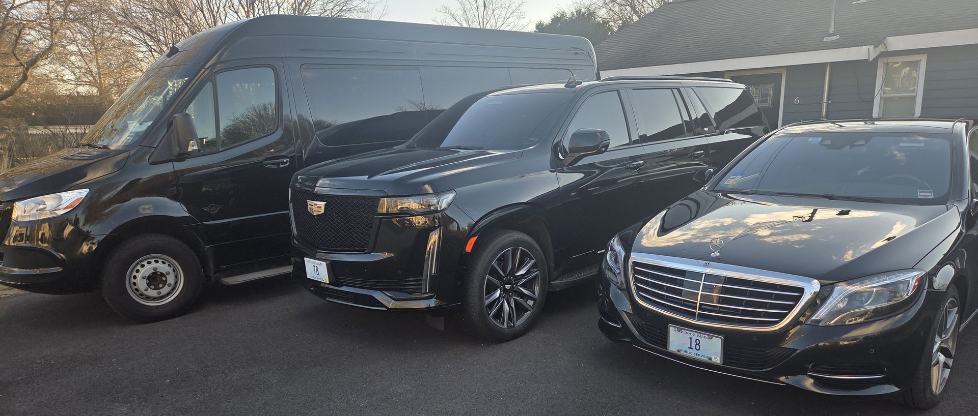 Three black luxury vehicles, including a van, an SUV, and a sedan, parked side-by-side on an asphalt lot.
