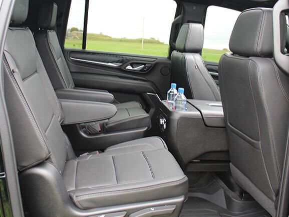 A view of a vehicle's second-row leather seats and center console with two water bottles.