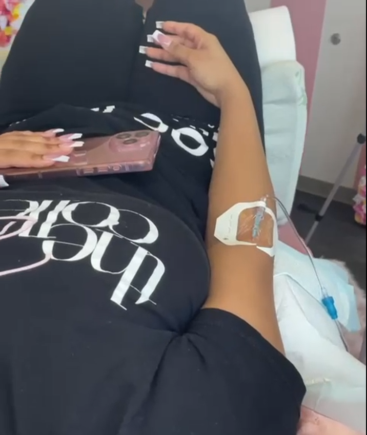 A woman is laying in a hospital bed with an iv in her arm from mobile iv therapy urbanrx health lounge in houston, tx