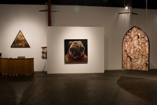 A painting of a pug dog is hanging on a wall in a museum.