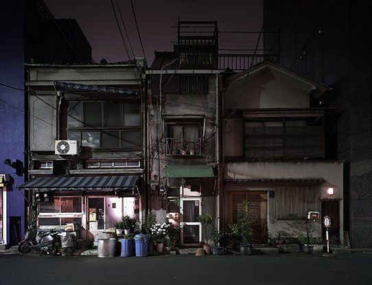 A row of buildings are lined up on a city street at night.