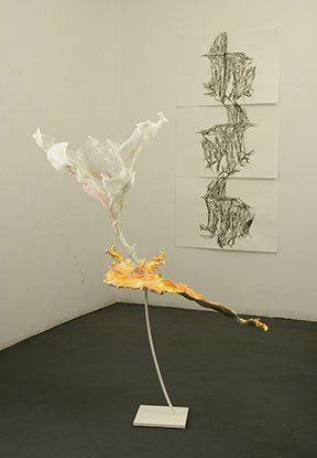 A sculpture is sitting on a stand in a room next to a wall.