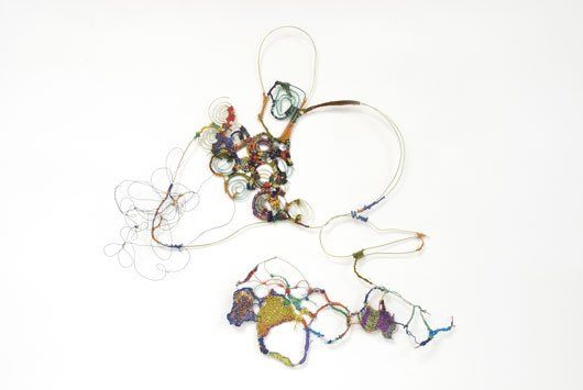 A close up of a colorful necklace on a white surface.