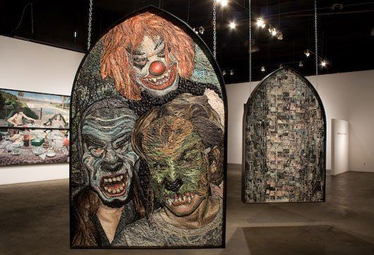 Three paintings of clowns are hanging on a wall in a museum.