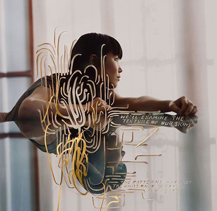 A woman is looking at her reflection in a mirror with the words we 'll examine the texture of our signs written on it