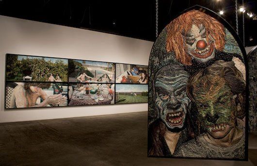 A painting of a clown is hanging on a wall in a museum.