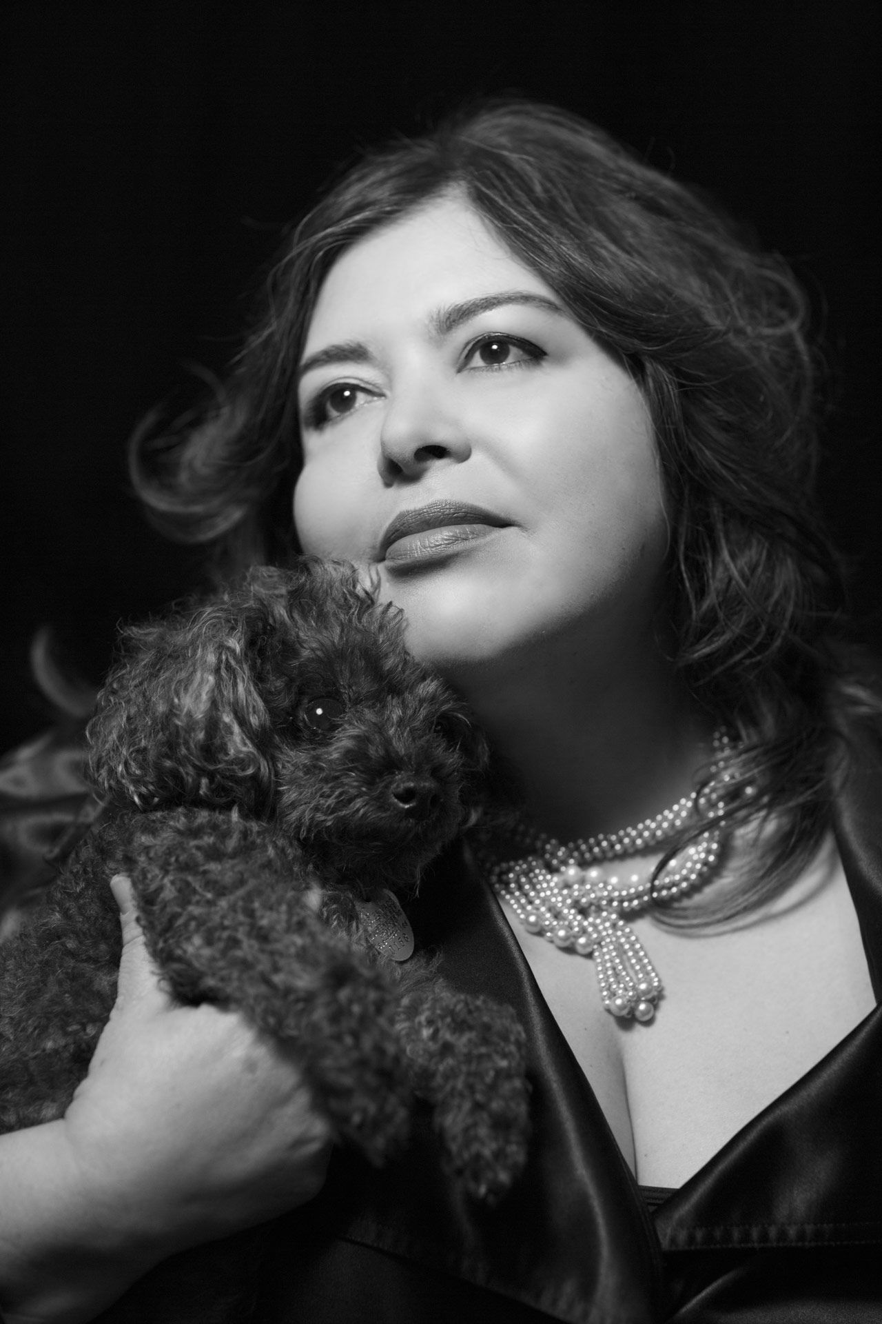 A woman is holding a small dog in her arms in a black and white photo.