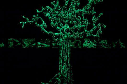 A green tree is glowing in the dark on a black background.