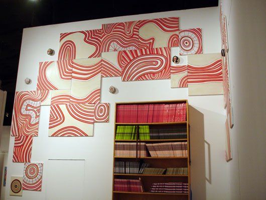 A room with a bookshelf and a wall with paintings on it