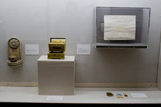 A display case with a statue , a box , and a piece of paper on it.