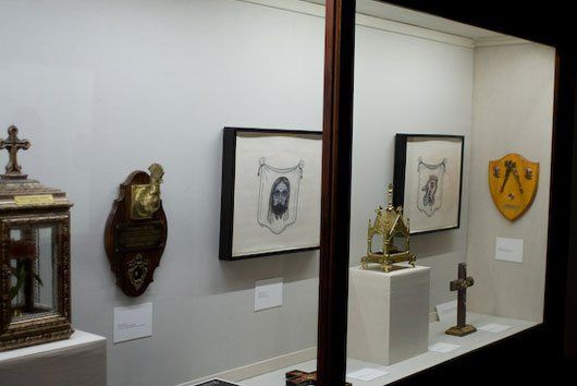 A display case filled with antique clocks , crosses , and shields.