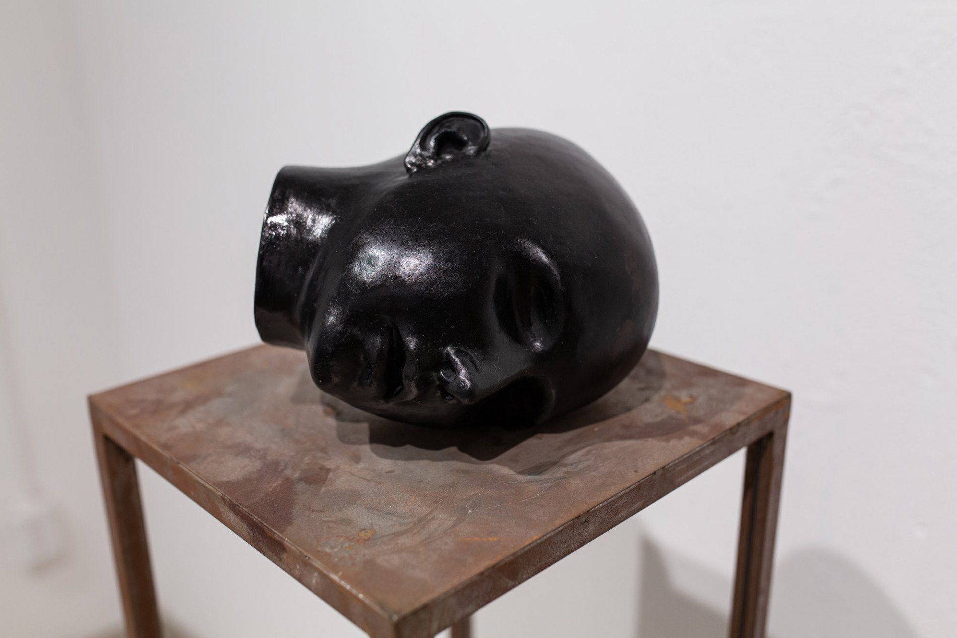 A black sculpture of a pig 's head is sitting on a wooden table.