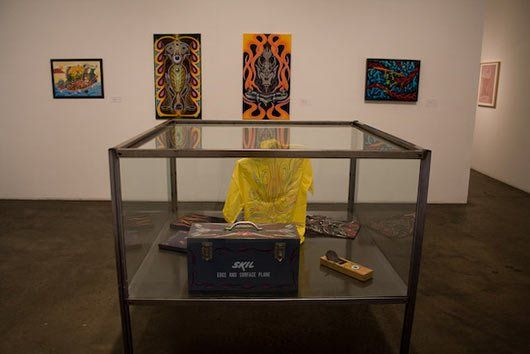 A display case with a yellow jacket and a black box on it in a museum.