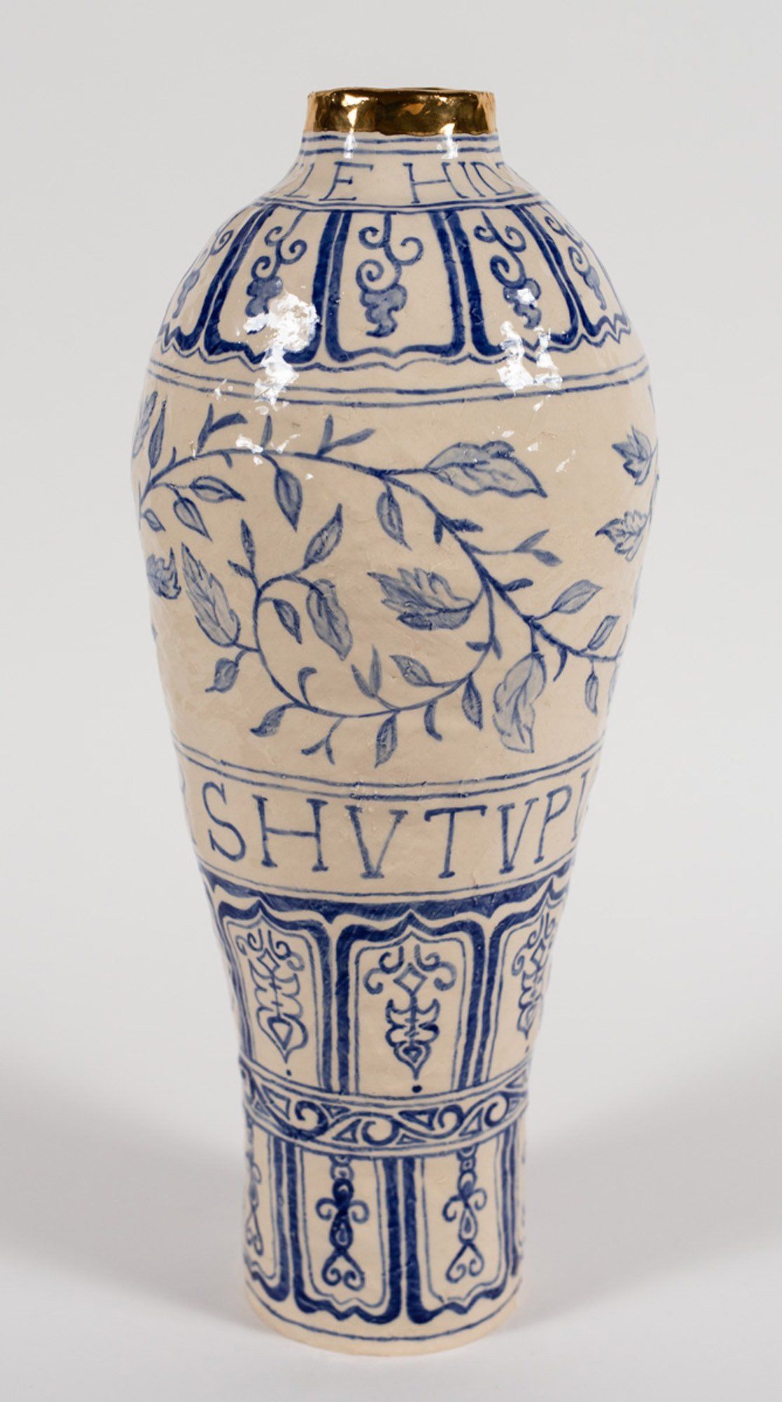 A close up picture of a white vase with blue leaves and letters on it.