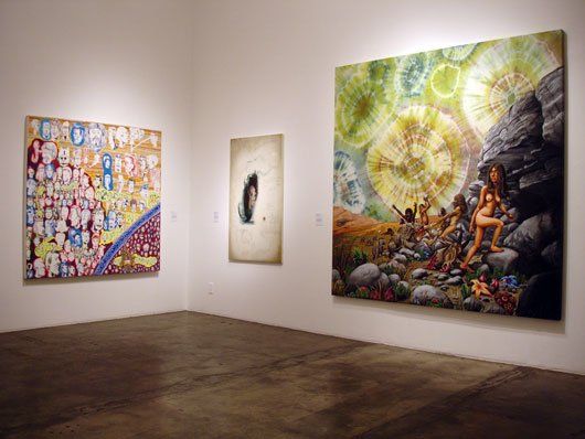 Three paintings are hanging on a wall in a room.