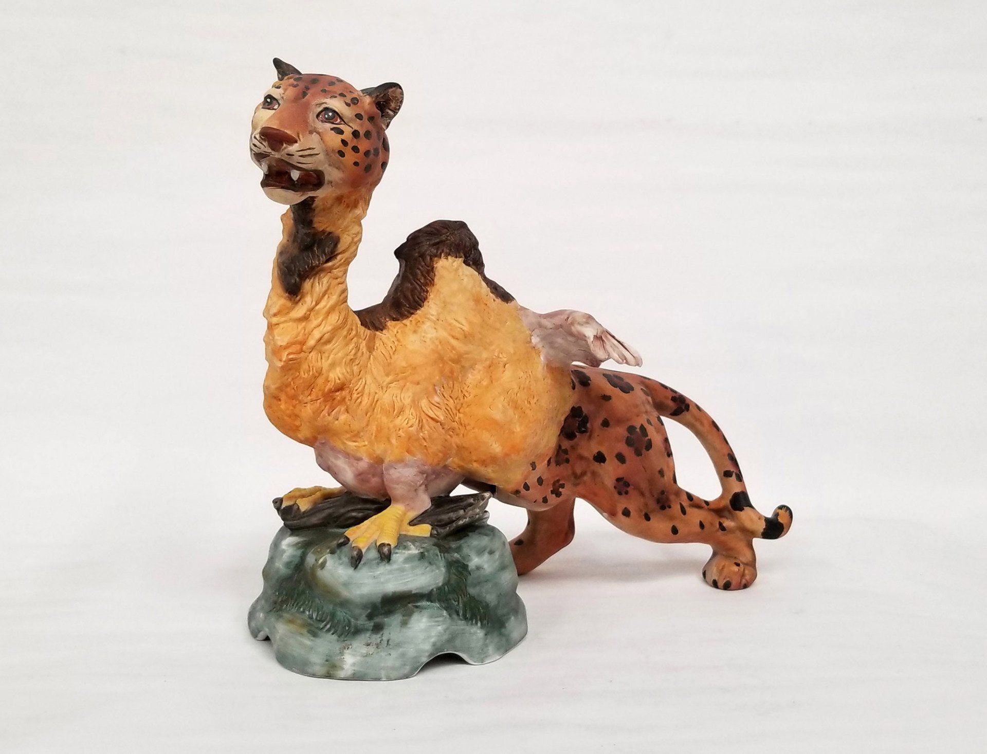 A statue of a leopard and a camel on a rock