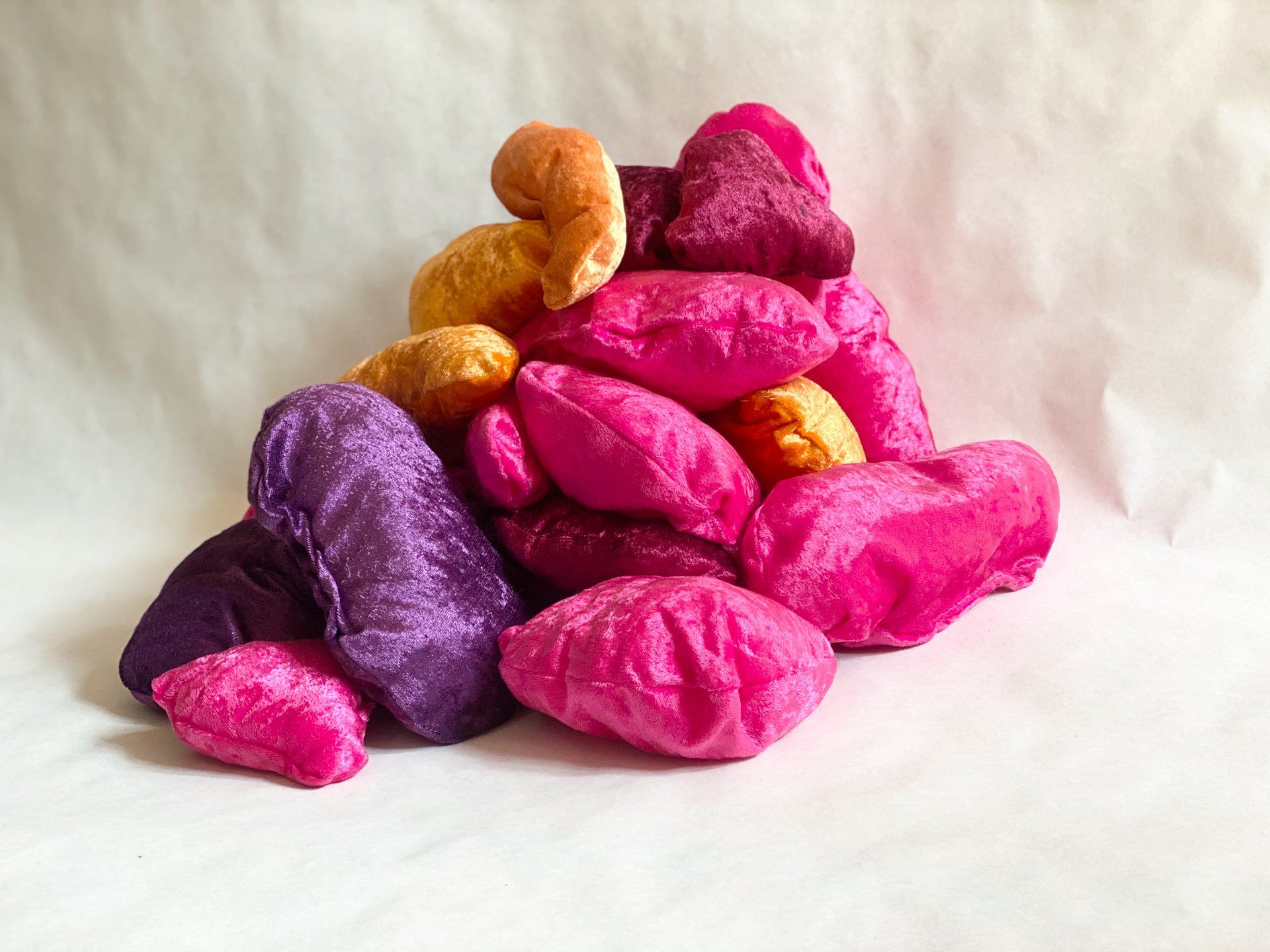 A pile of pink and purple pillows on a white surface