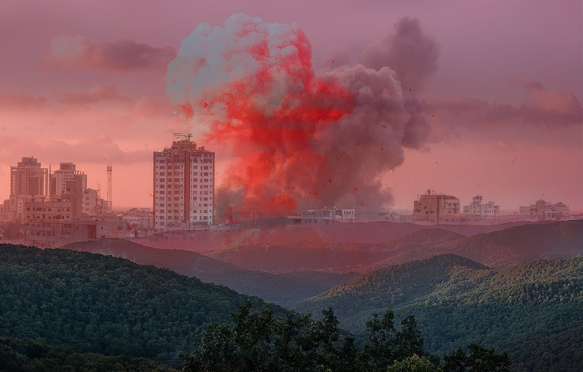 A double exposed photograph of a mushroom cloud from a bomb exploding in a city and rolling green mountains.
