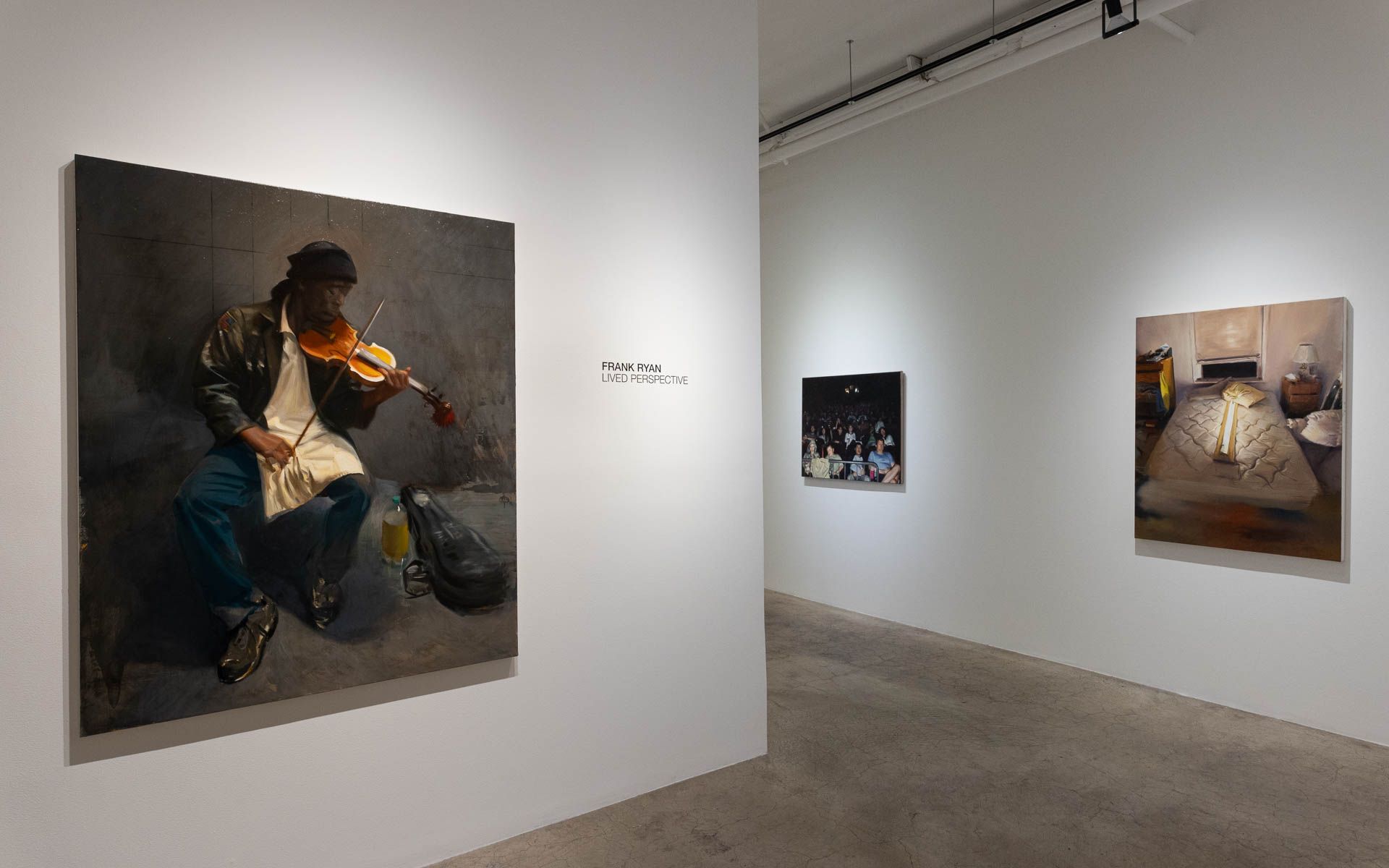 A painting of a man playing a violin is hanging on a wall in a museum.