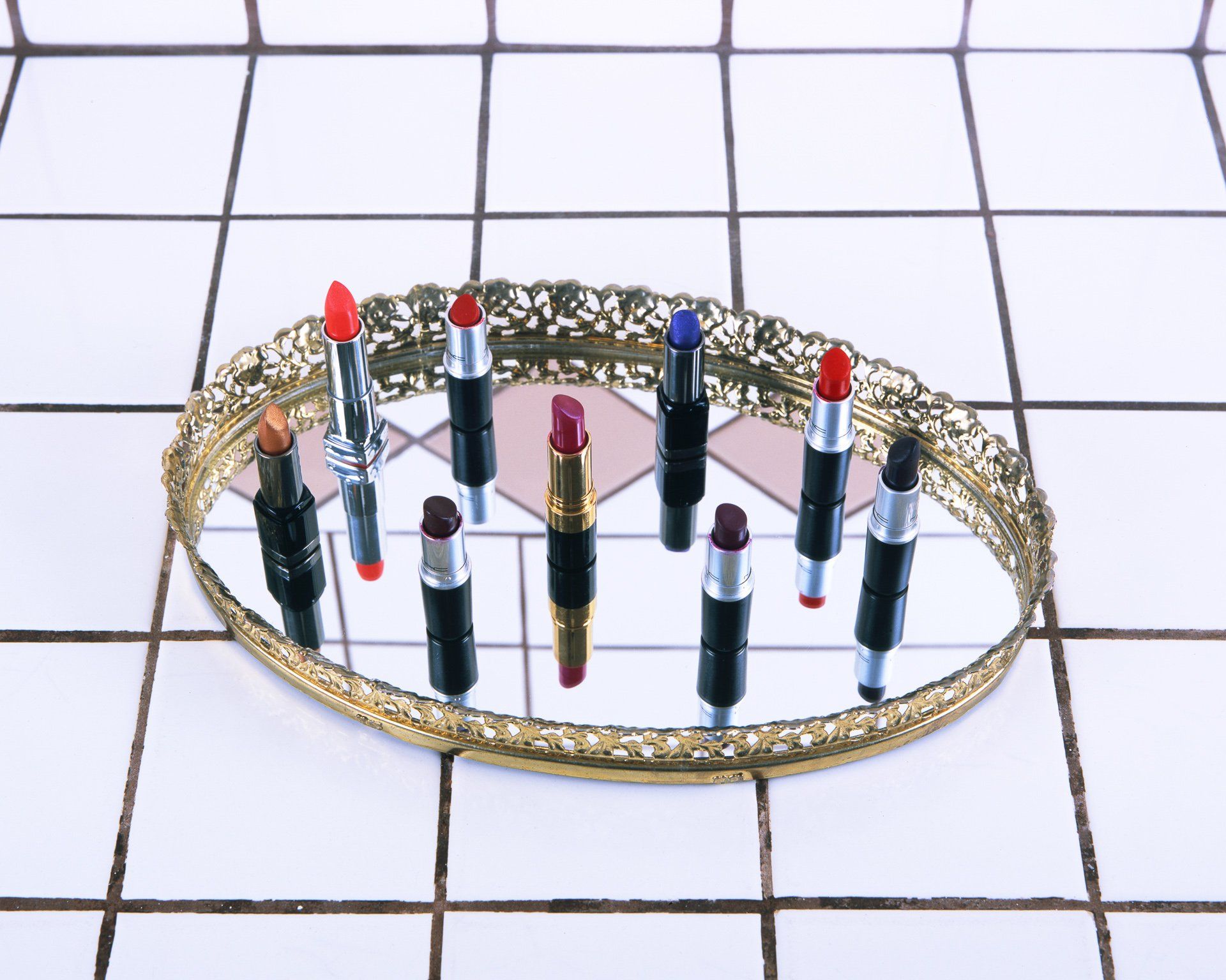 A tray of lipsticks sits on a tiled floor