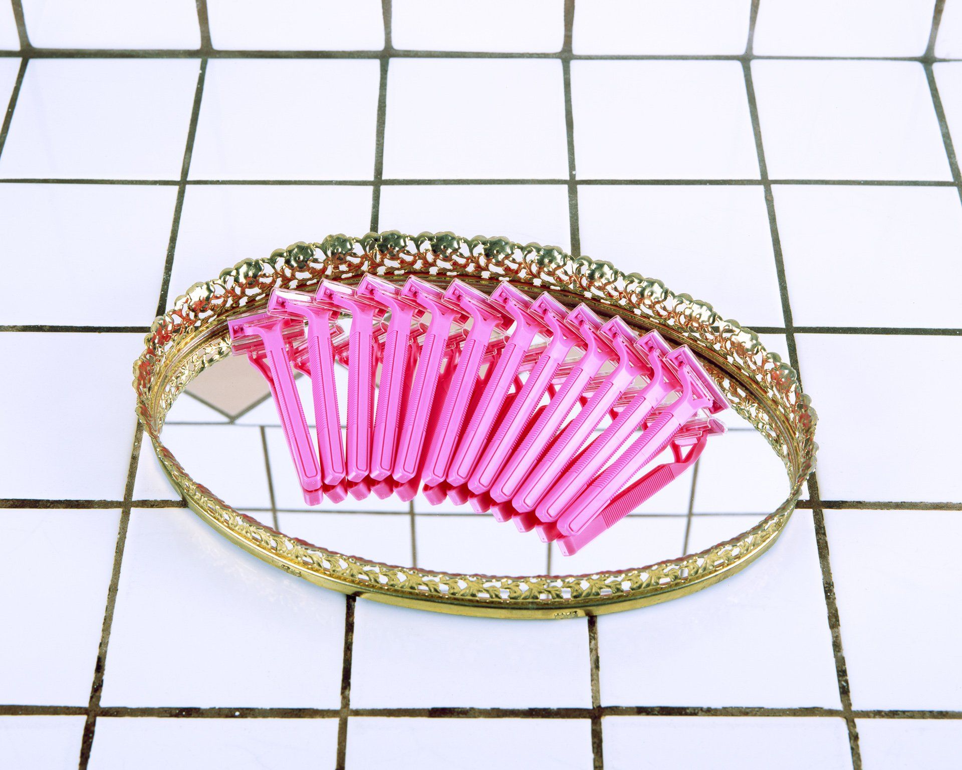 A tray of pink razors sits on a tiled floor