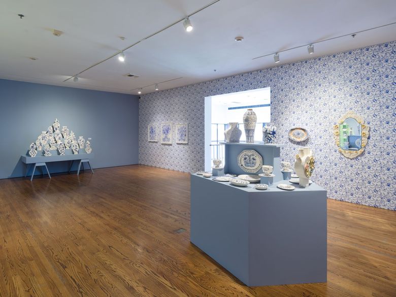 A double exposed photograph of a mushroom cloud from a bomb exploding in a city and rolling green mountains.