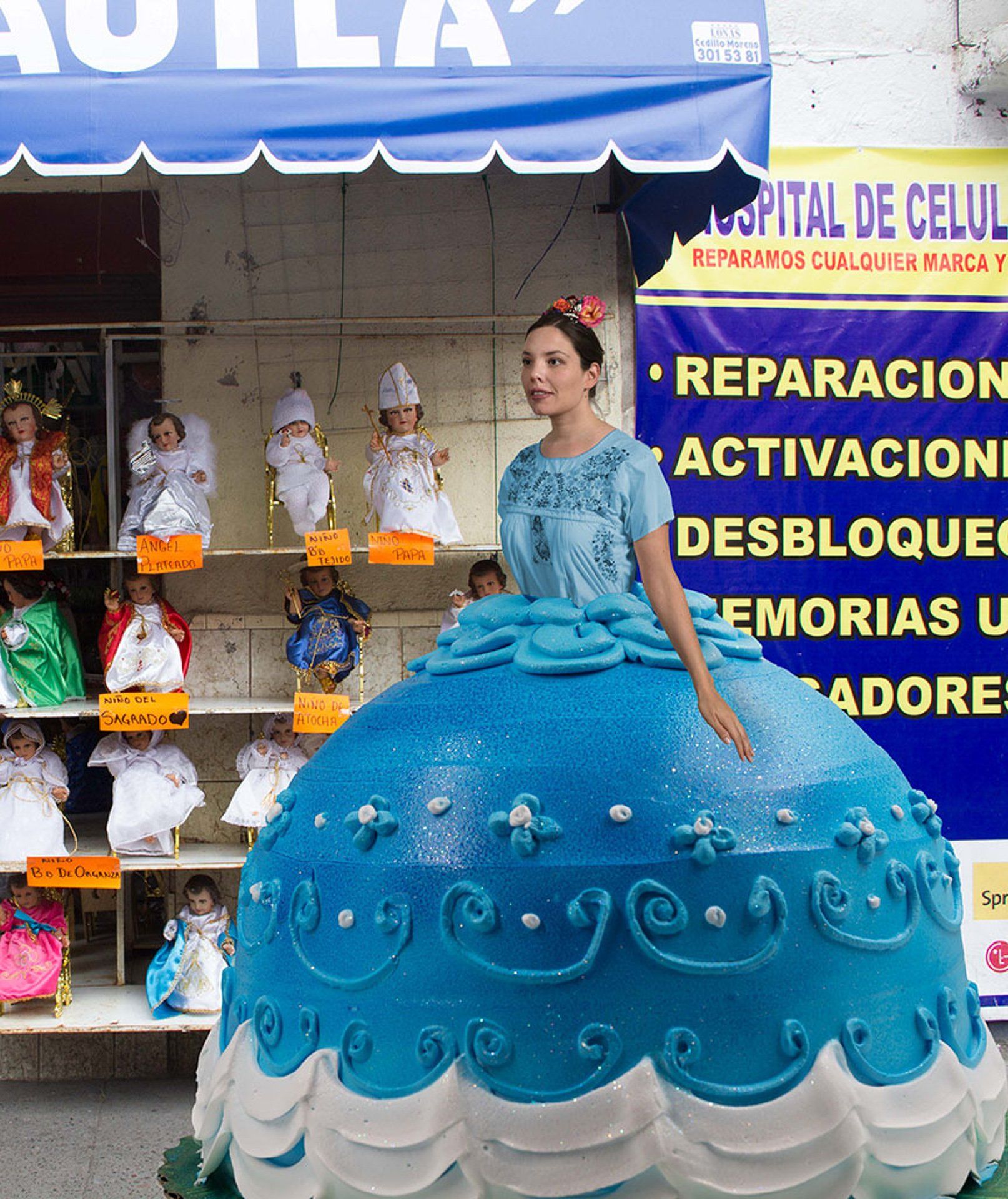 A woman in a blue dress stands in front of a sign that says hospital de cerveza