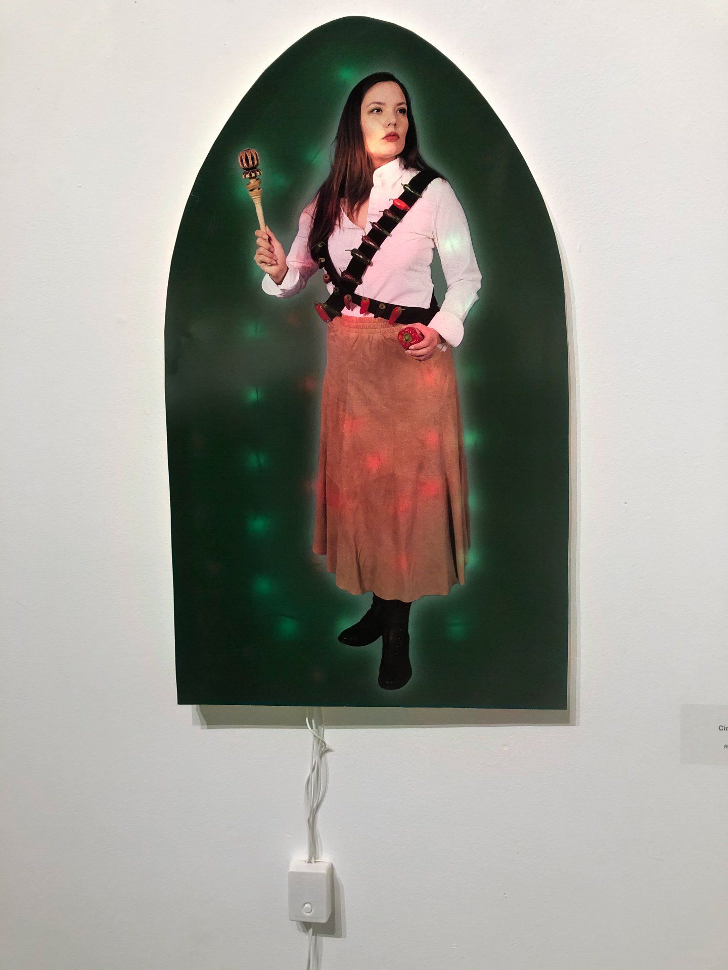 A painting of a woman holding a wand is hanging on a wall.