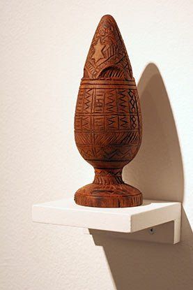 A wooden sculpture is sitting on top of a white shelf.