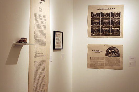 A room with a newspaper on the wall and a picture on a shelf.