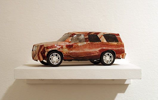 A car sculpture is sitting on a white shelf.