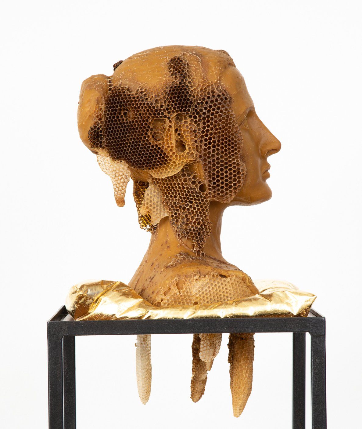 A statue of a woman 's head made of bees on a stand.