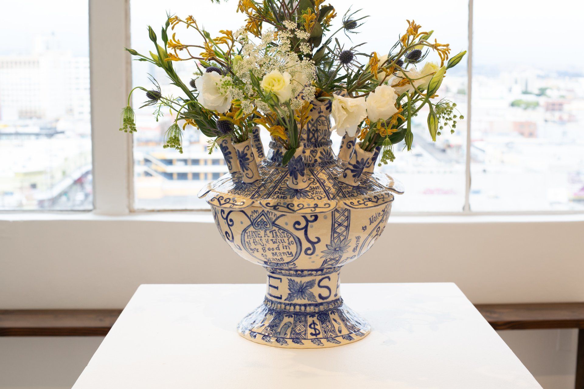 A blue and white vase filled with flowers is sitting on a table in front of a window.