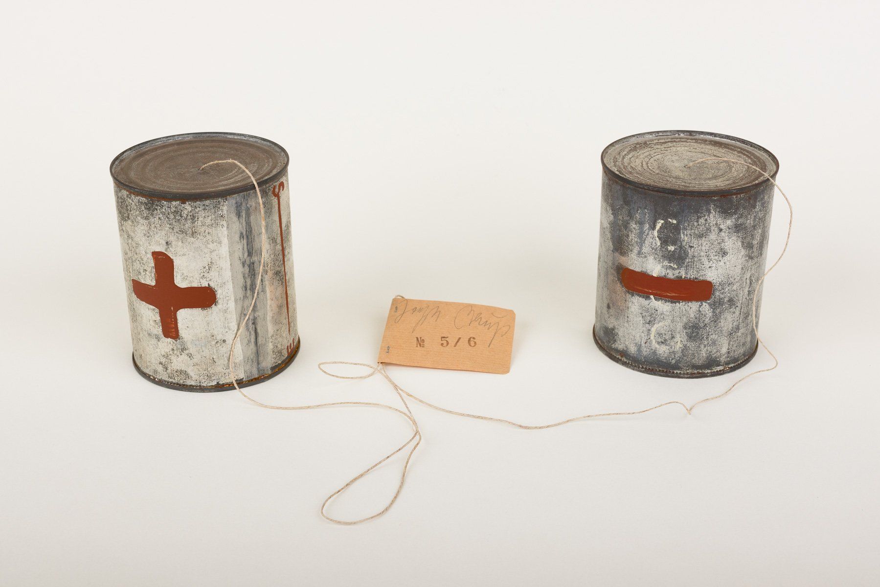 Two tin cans with a red cross on them are connected by string.