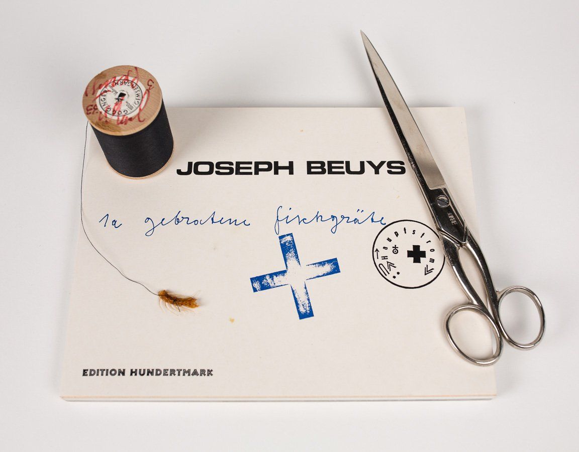 A joseph beuys card with a spool of thread and scissors