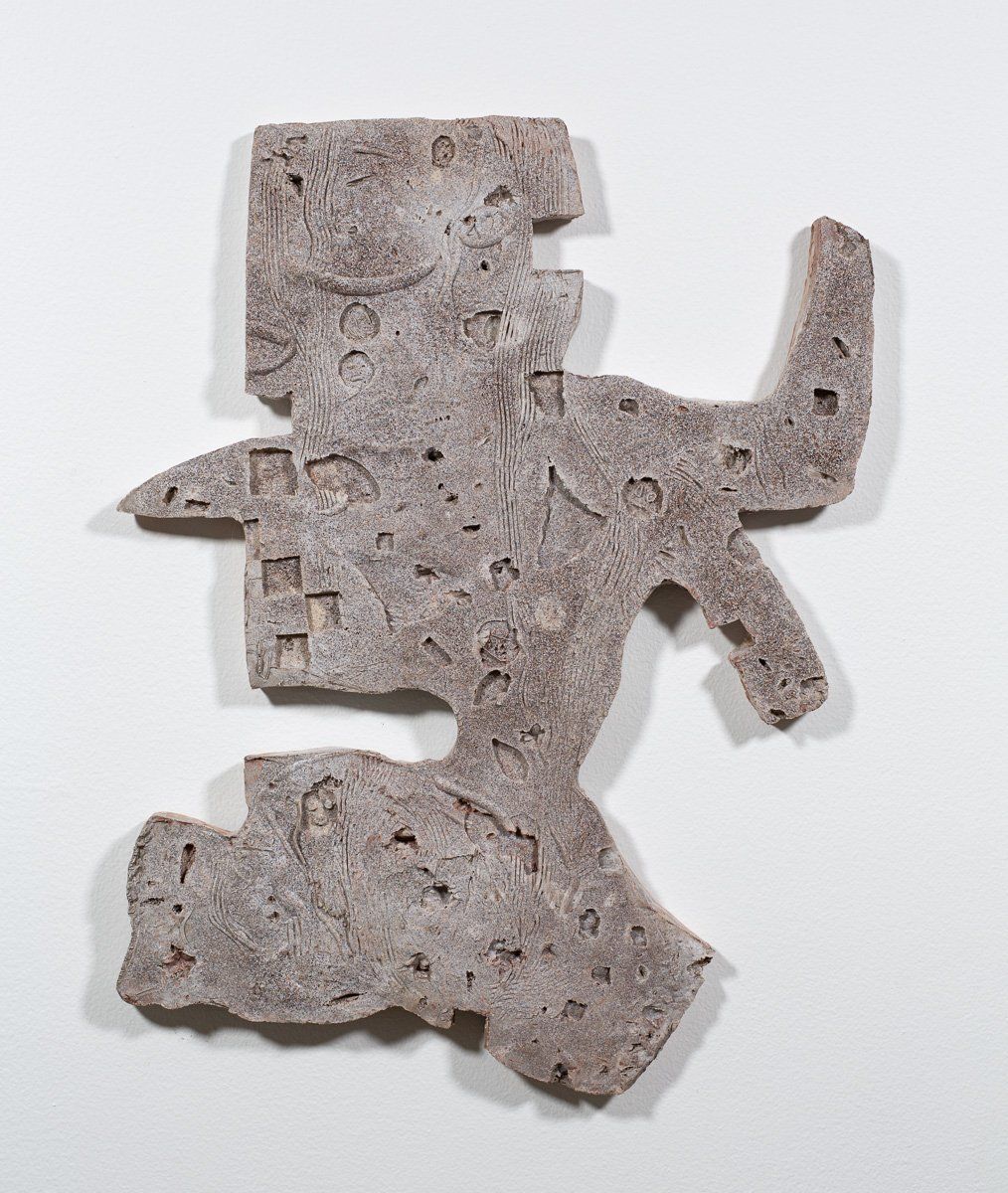 A piece of concrete that looks like a statue on a white surface