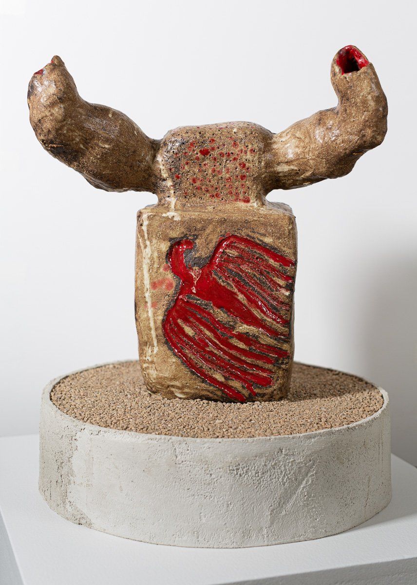 A sculpture of a bull 's head is sitting on top of a concrete base.