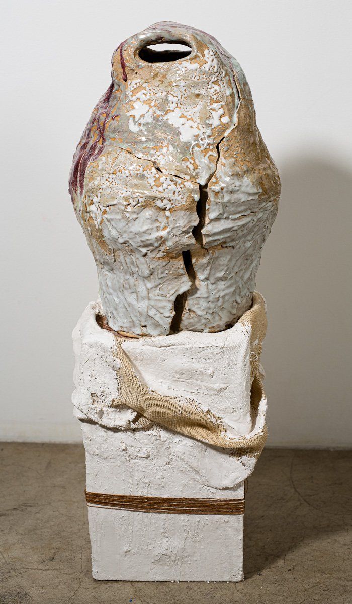 A statue of a bird is sitting on top of a white block.