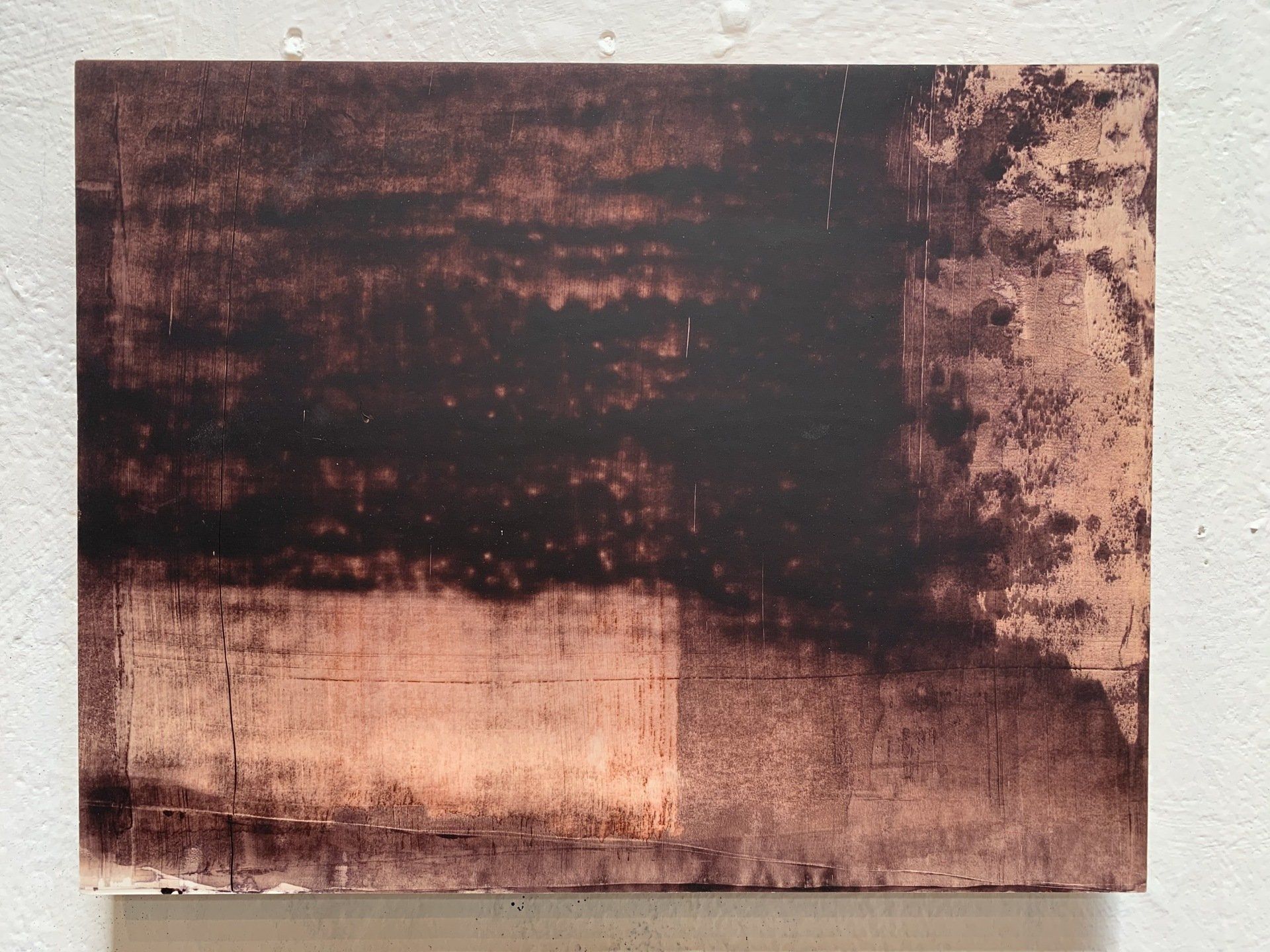 A brown and black painting on a white wall