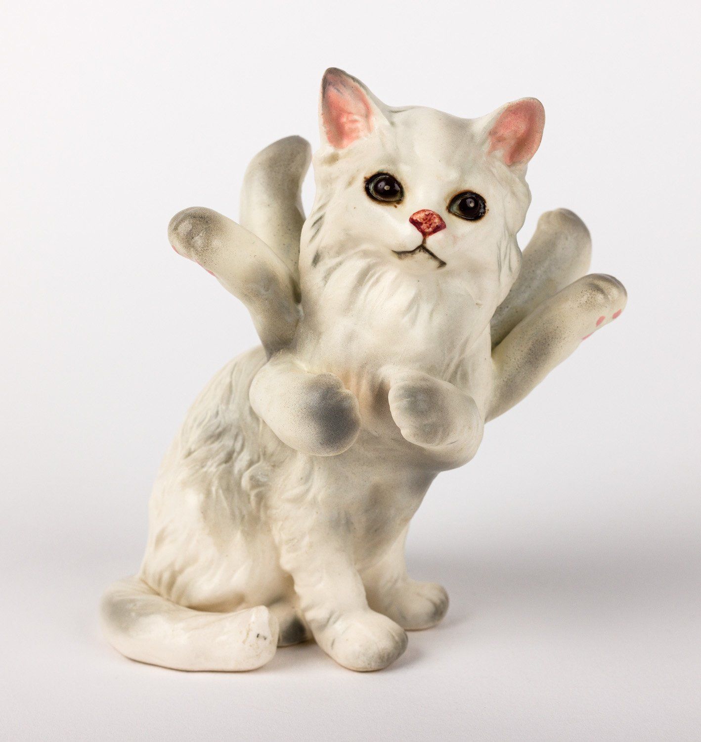 A statue of a white cat with many arms and legs