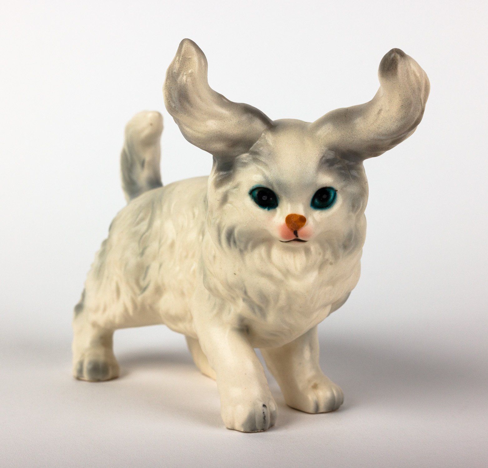 A figurine of a cat with horns and blue eyes