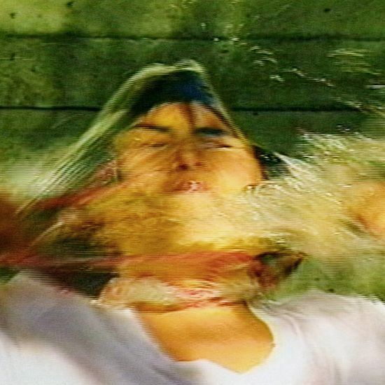 A woman is laying in the water with her eyes closed and her hair blowing in the wind.