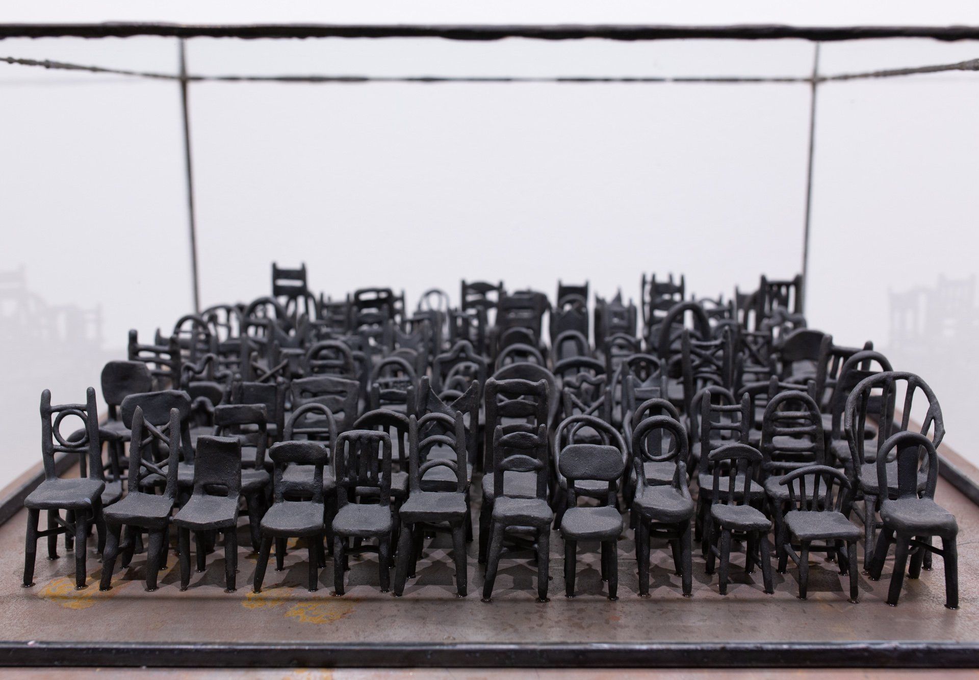 A row of black chairs in a glass case